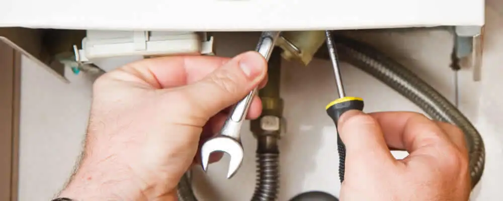 Boiler repair technician tightening pipe fittings and connections in Boulder, CO