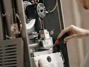 Furnace repair technician inspecting internal components and wiring in Boulder, CO