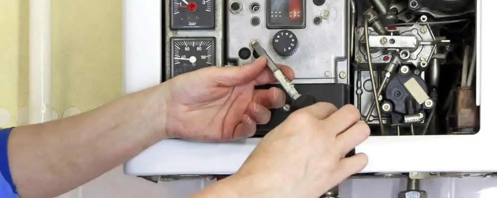 Heating repair technician adjusting boiler controls and components in Boulder, CO