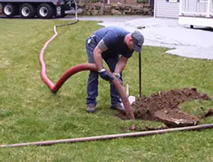 Septic pumping technician servicing a residential septic tank with a vacuum hose in Boulder, CO