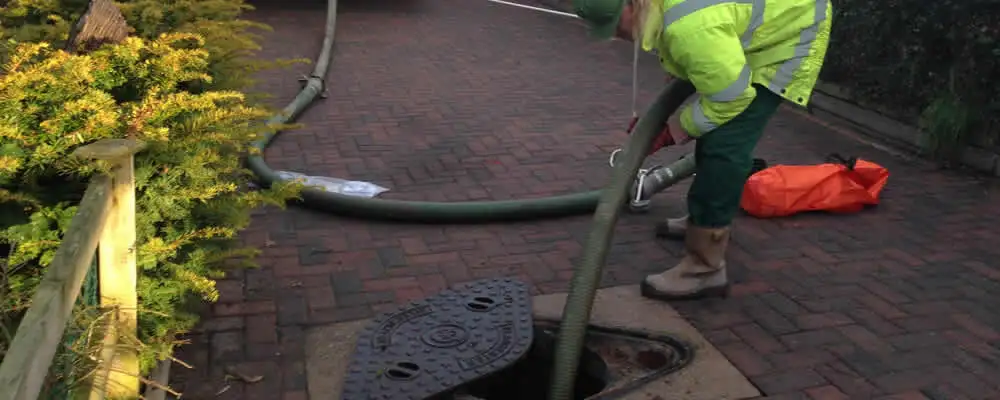 Septic tank cleaning technician servicing a septic tank with a vacuum hose in Boulder, CO