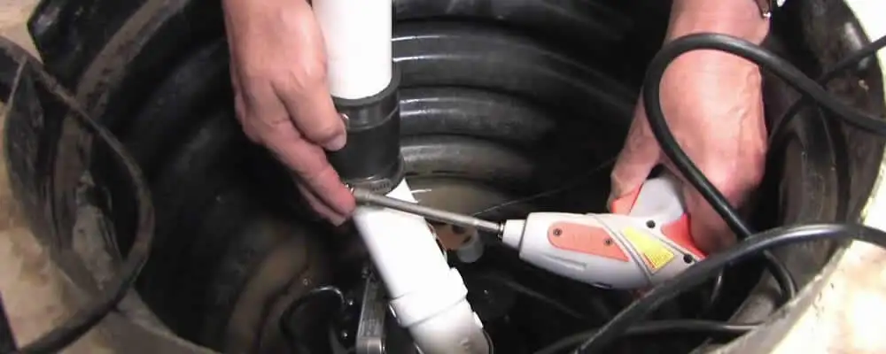 Sump pump installation technician connecting PVC discharge piping in Boulder, CO