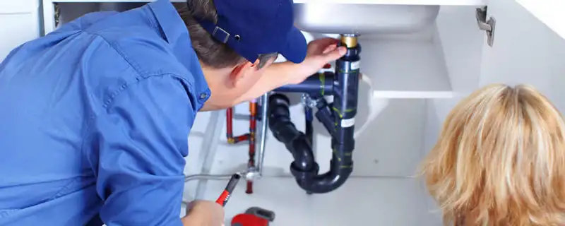 Plumber repairing under-sink drain pipes and fittings in Boulder, CO